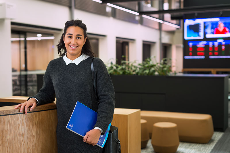 Student smiling leaning on a concierge desk in the UniSA Business area at City West campus