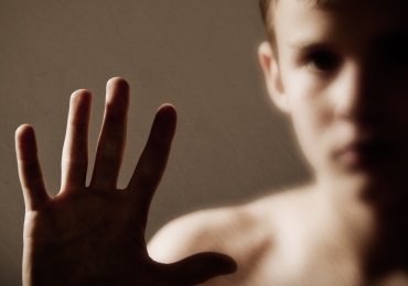 image of a boy with his hand up against a pane of glass