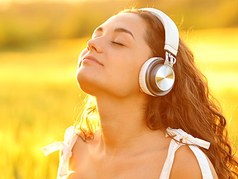 Woman wearing headphones outside in the sun