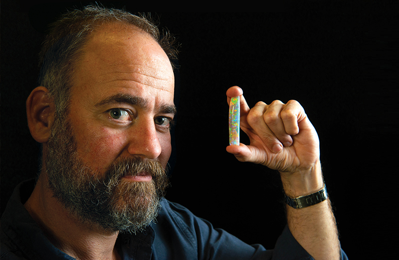 Tim Gilchrist with the Virgin Rainbow, the world’s most expensive opal. The opalised ‘pen’ of an extinct species of cuttlefish, called Belemnite, is said to glow in the dark. Photo by Brenton Edwards.