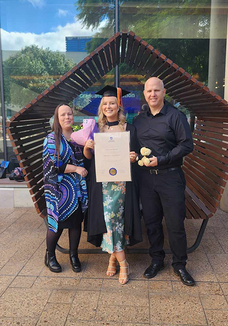 Nikia with her UniSA Alumni parents at her graduation ceremony