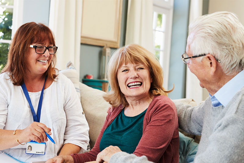Teacher smiling with two elderly people in a aged care facility