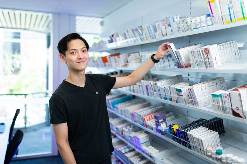 Pharmacy student grabbing medicine off on a pharmacy shelf