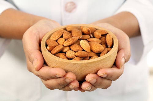 Hands holding wooden bowl of almonds
