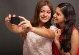 Two teenage girls taking a selfie with their mobile phone