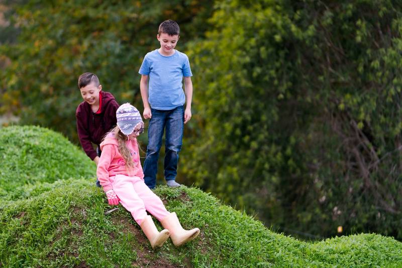 3 kids on a grassy hill