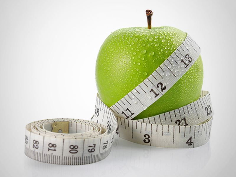 Tape measure wrapped around a green apple