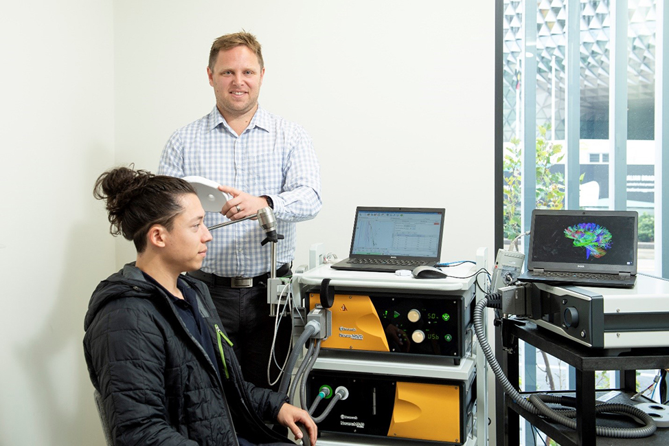 Dr Brenton Hordacre at the UniSA Health and Medical Clinic with his rTMS technology working to tackle post-stroke depression