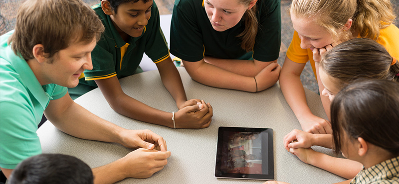 A teacher and students working with a tablet device