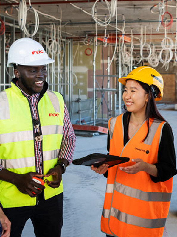 Graduates in high-vis talking on a building site