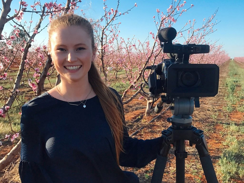 Brittany Evins, Journalist at ABC News, reporting from an orchard in blossom