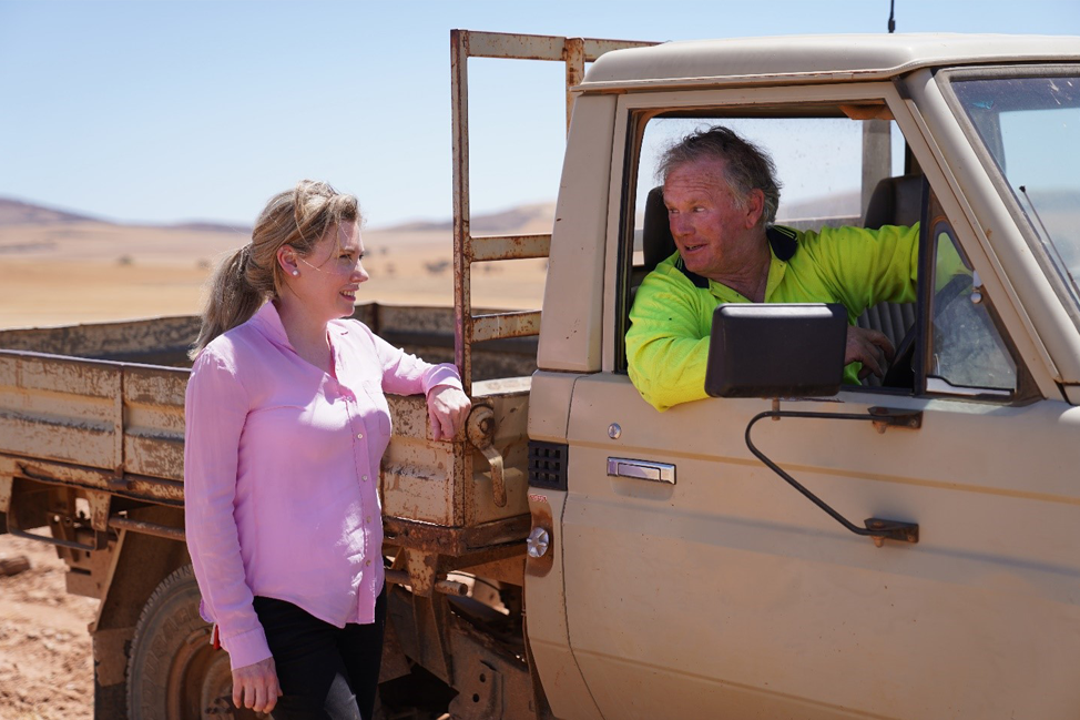 Dr Kate Gunn on the land talking with a farmer in his ute.