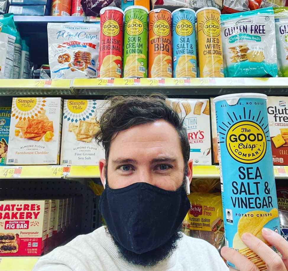Matt in a supermarket isle holdingThe Good Crisp Company Sea Salt & Vinegar potato crisps