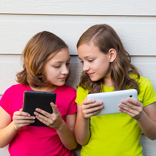 Two young girls looking at ipads together