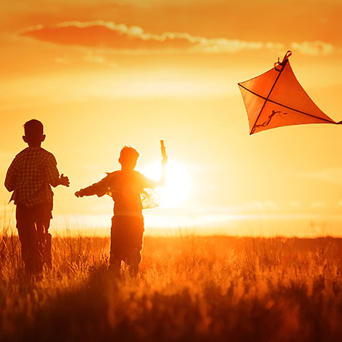 Kids flying kite at sunset