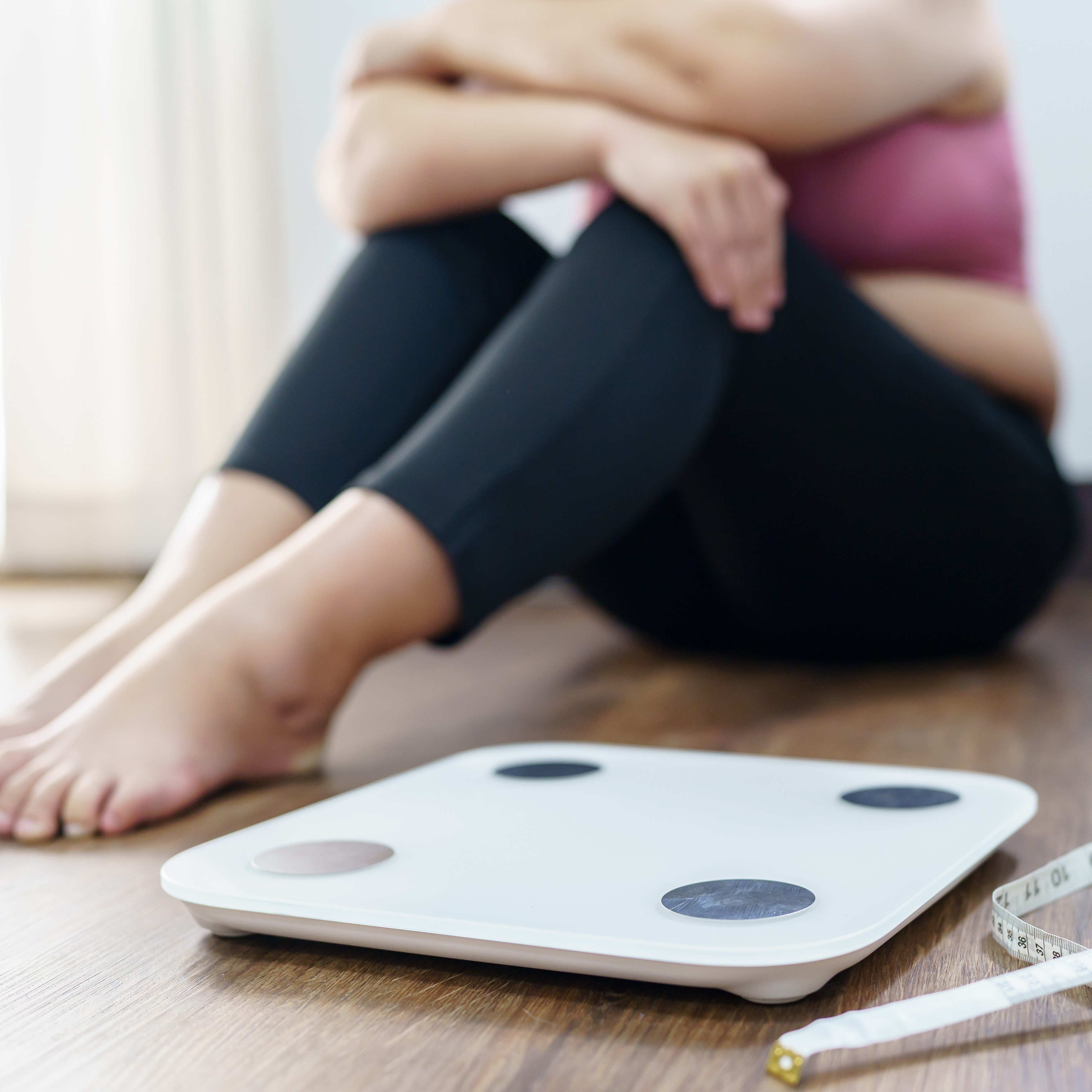 Women hugging her body in front of weight scales