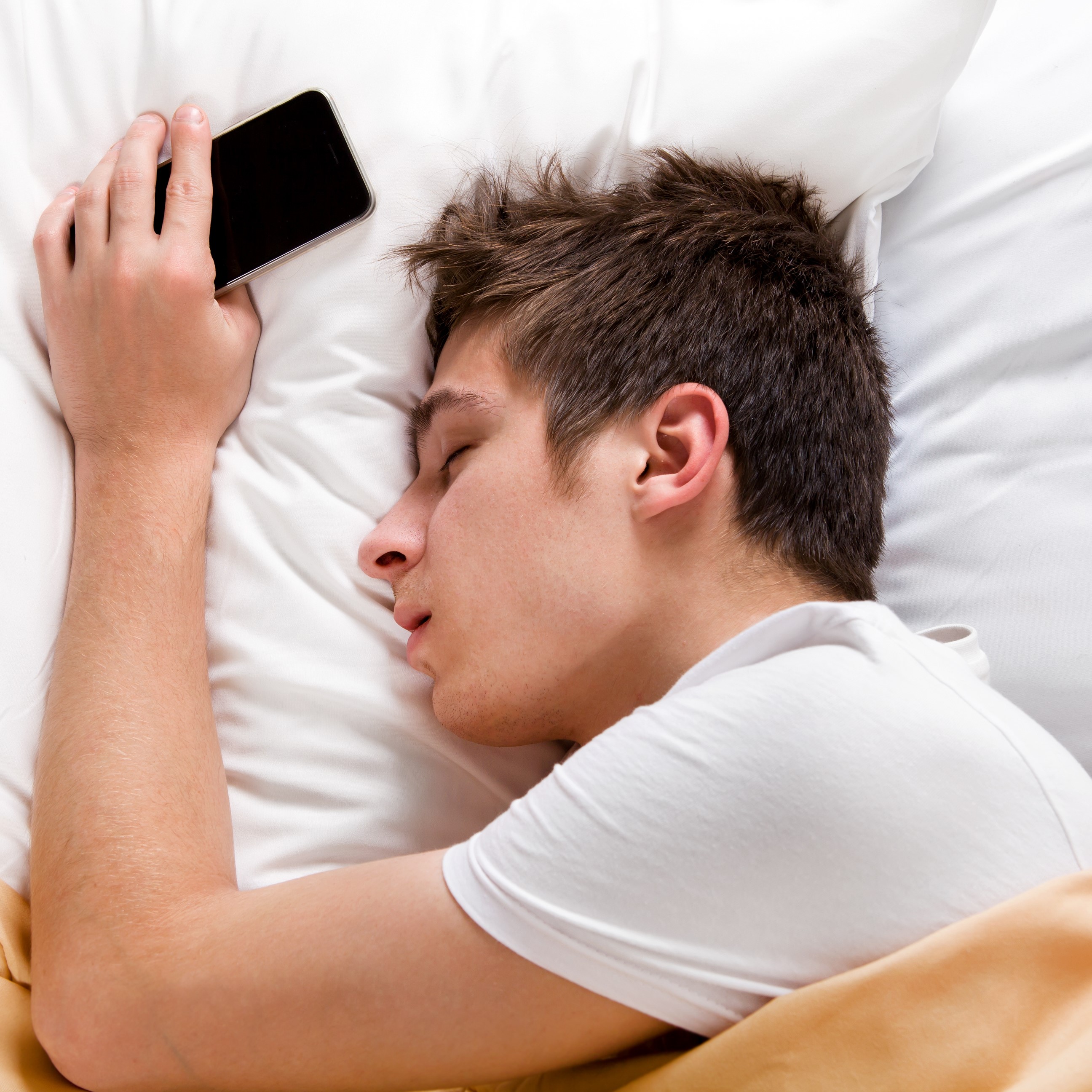 teenage boy fast asleep with mobile phone in hand