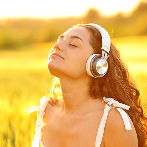 Girl with headphones on meditating in sun