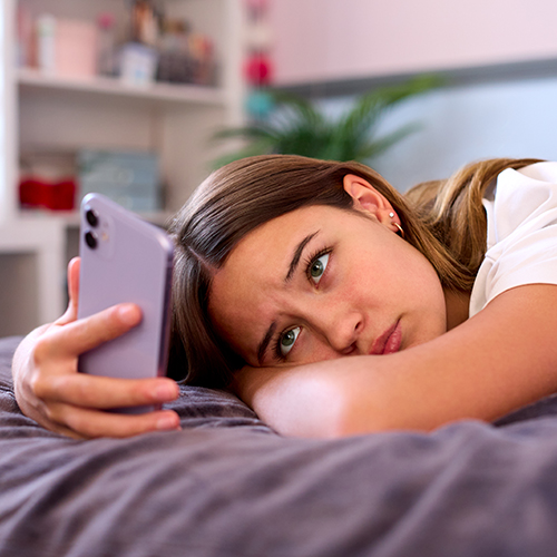 Anxious teenage girl holding her mobile phone