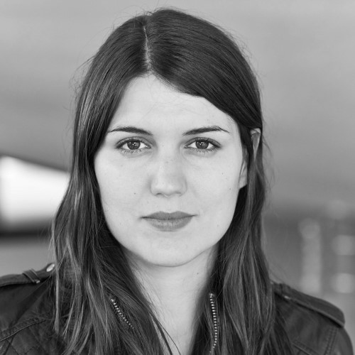 Black and white portrait of Alex Martinis Roe, a Caucasian female with long brown hair wearing a black leather jacket.jpg