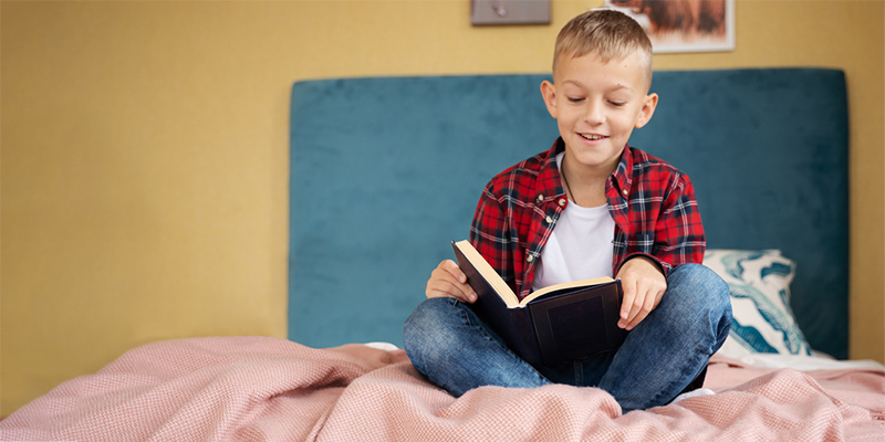 Boy reading a book on a bed