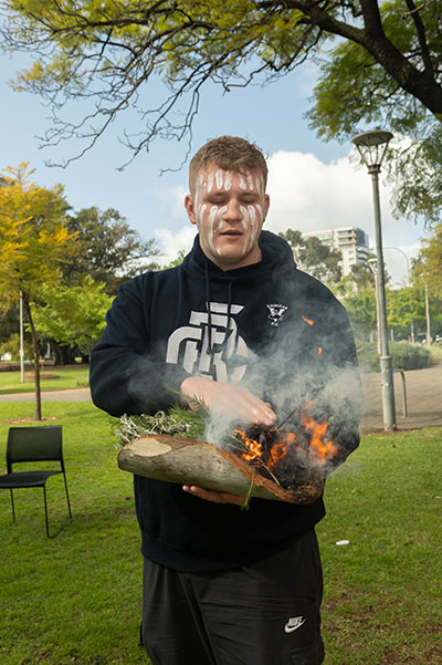 Kaurna and Ngarrindjeri man Isaac Hannam performs a smoking ceremony at the launch of the UniSA 2023-2025 Stretch RAP.